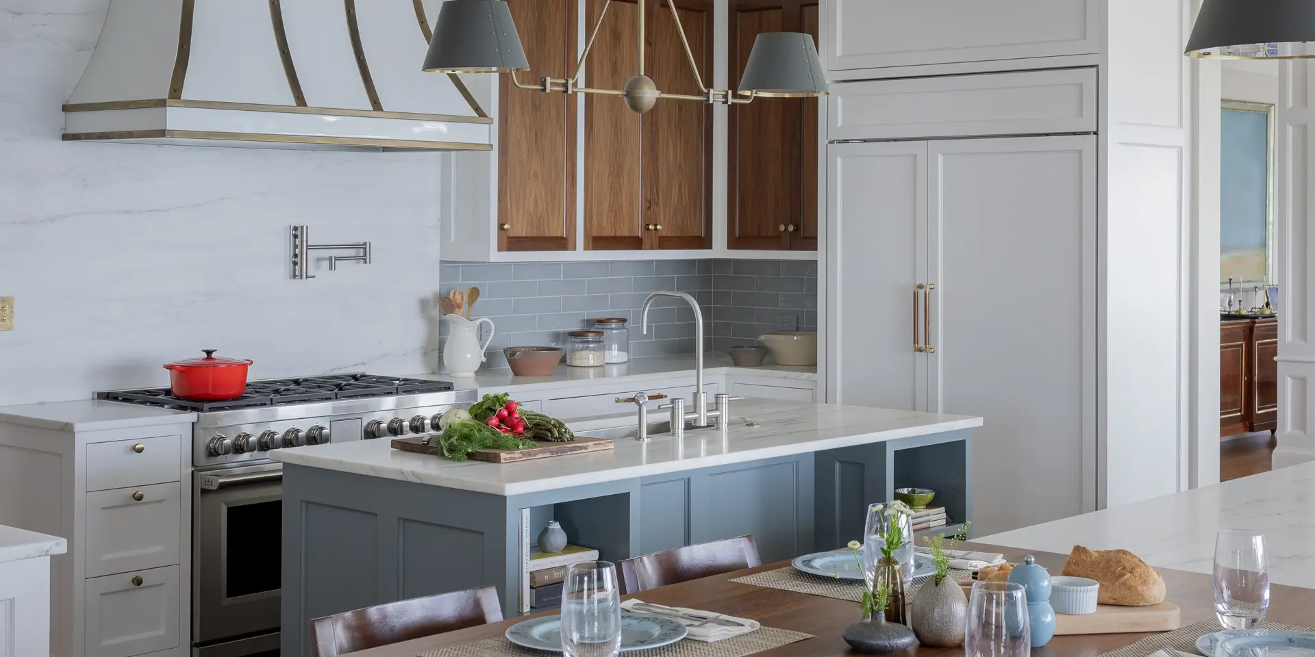 A modern-coastal kitchen blending warm wood, soft blue cabinetry, and refined brass accents.